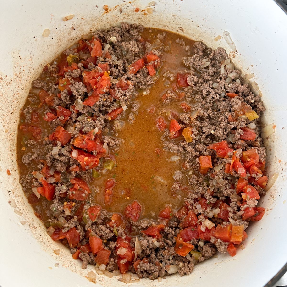 Pot with ground beef and diced tomatoes. 