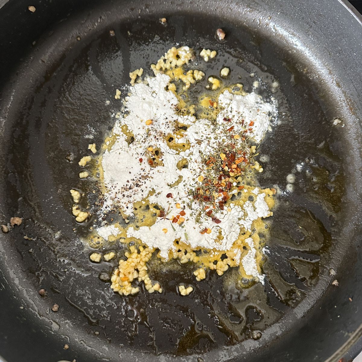 Skillet with garlic, flour, and seasonings. 