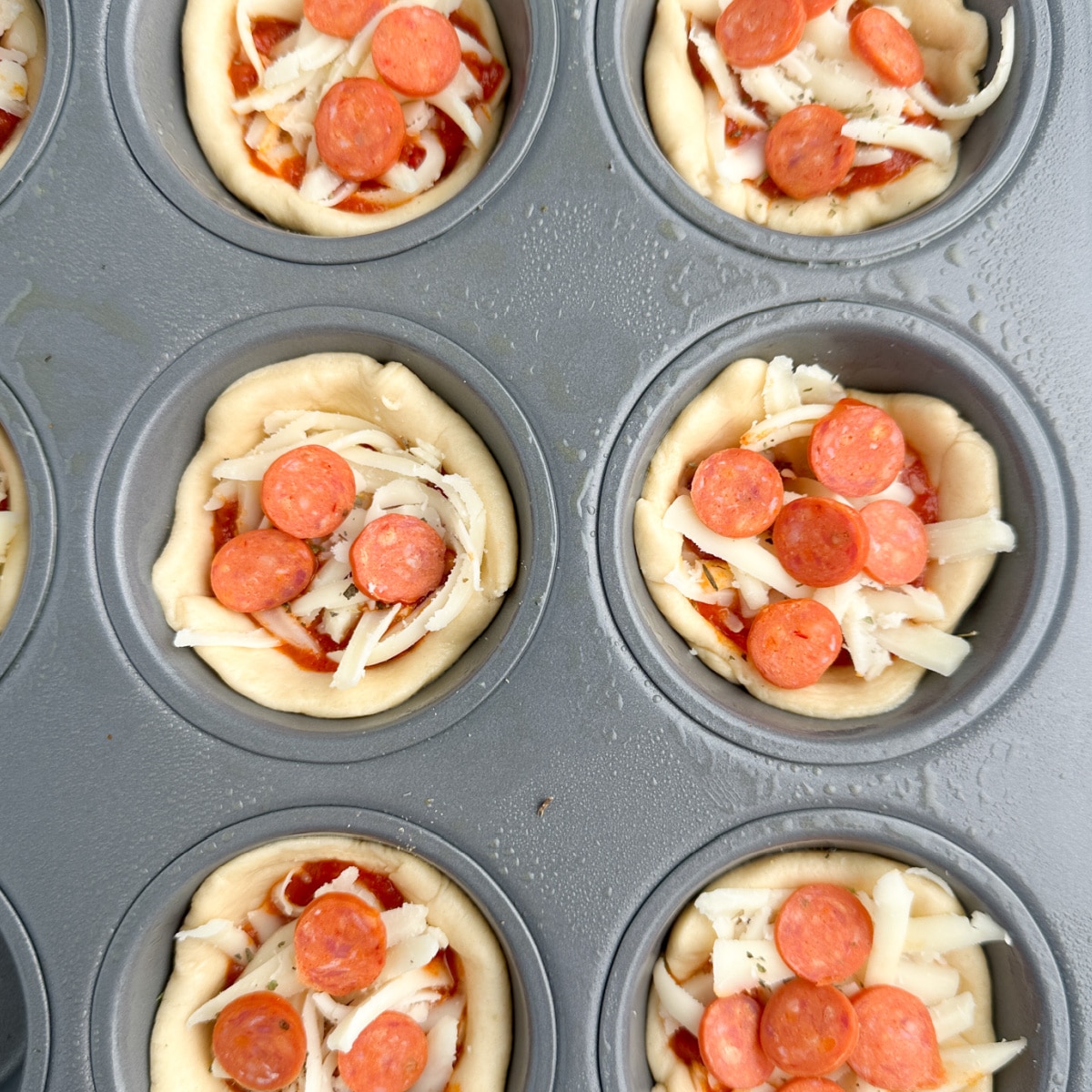 Uncooked pizza cupcakes in a muffin tin. 