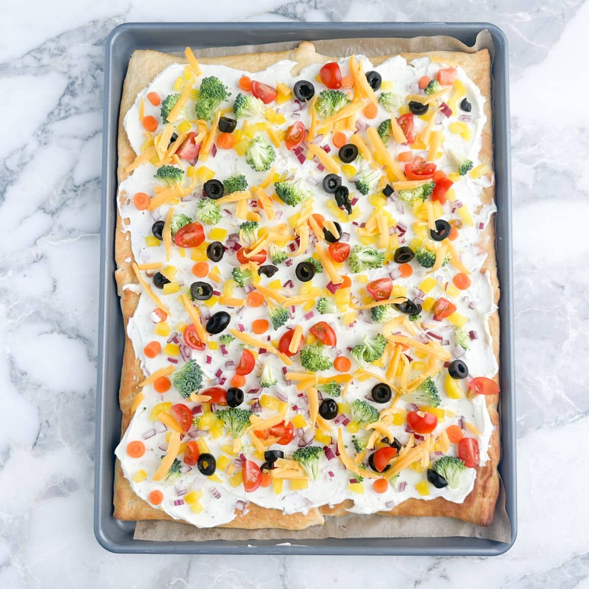 Crescent roll vegetable pizza on a baking sheet. 