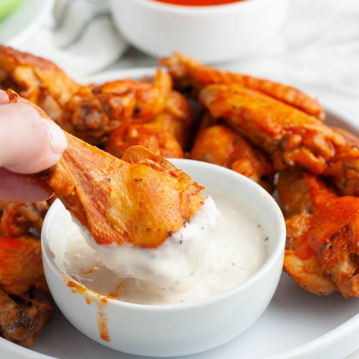 Chicken wing dipping in ranch sauce. 