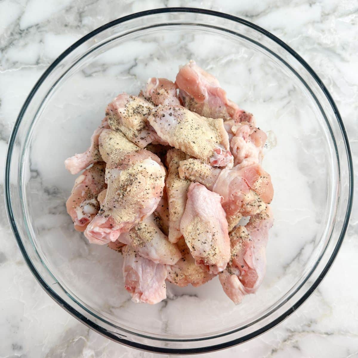 Bowl full of uncooked chicken wings. 