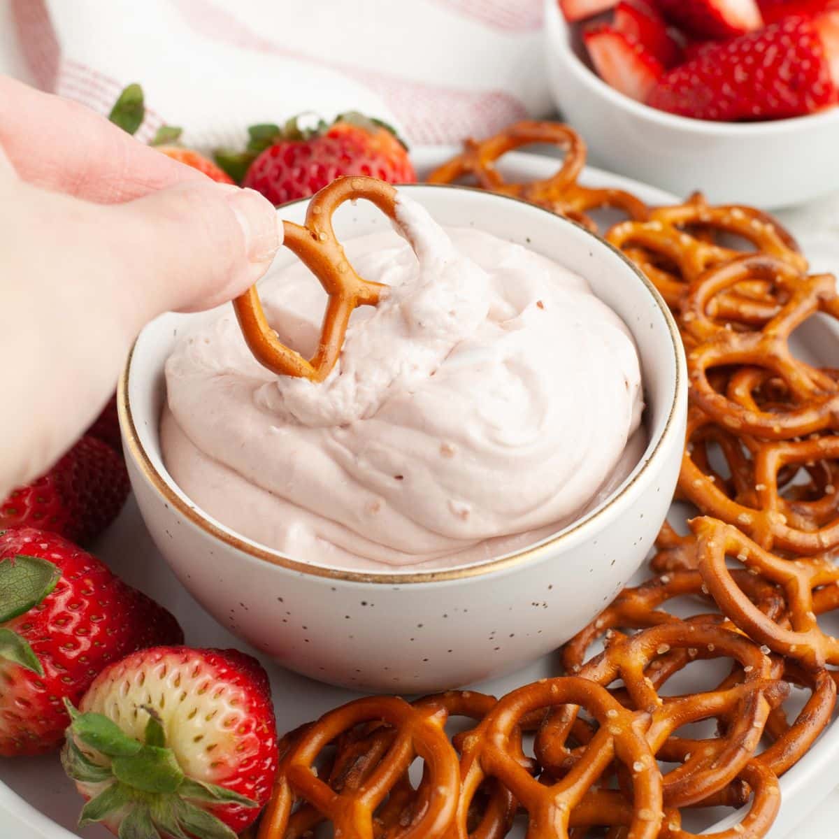 Bowl of strawberry dip with a pretzel. 