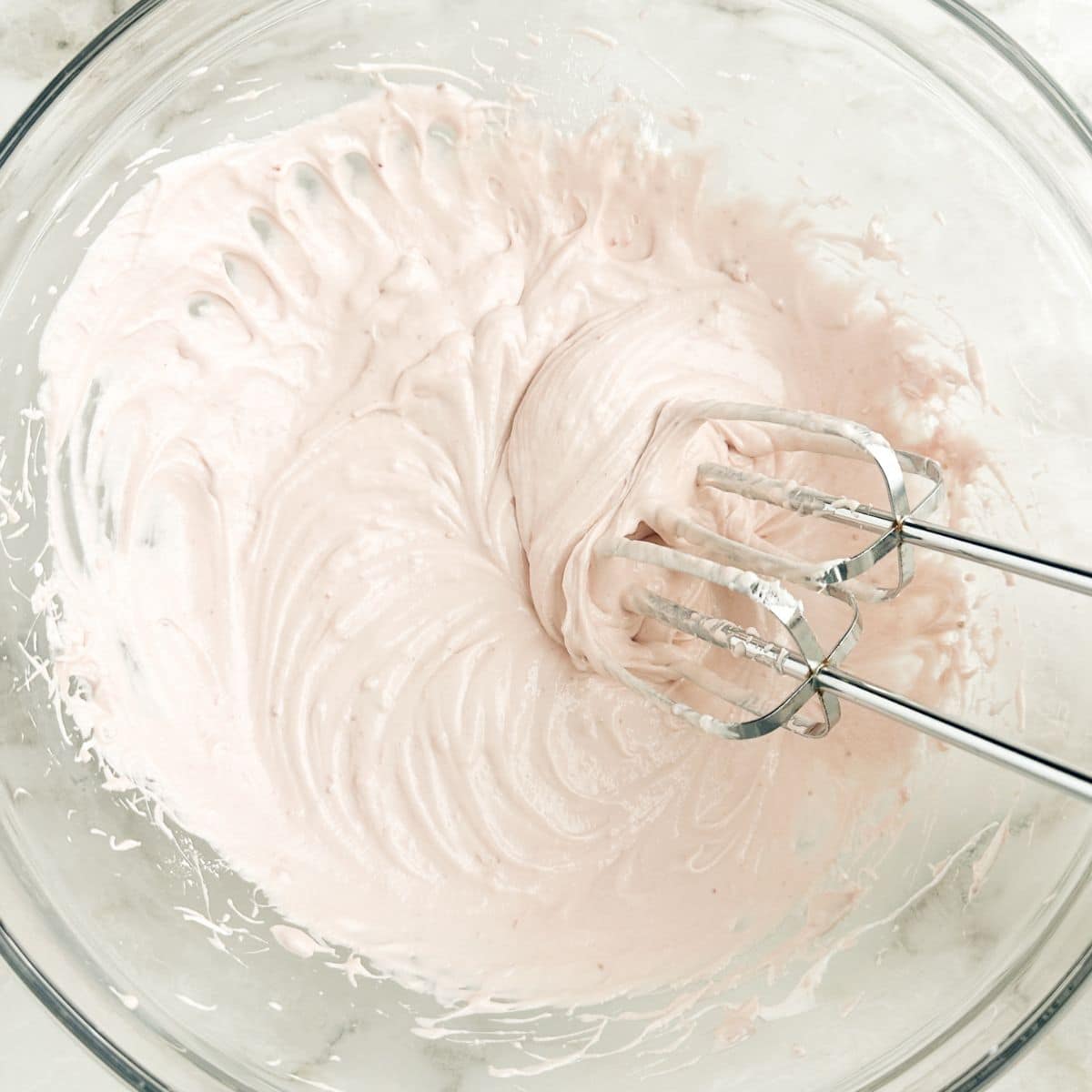 Bowl with a strawberry cream cheese mixture and electric mixer. 