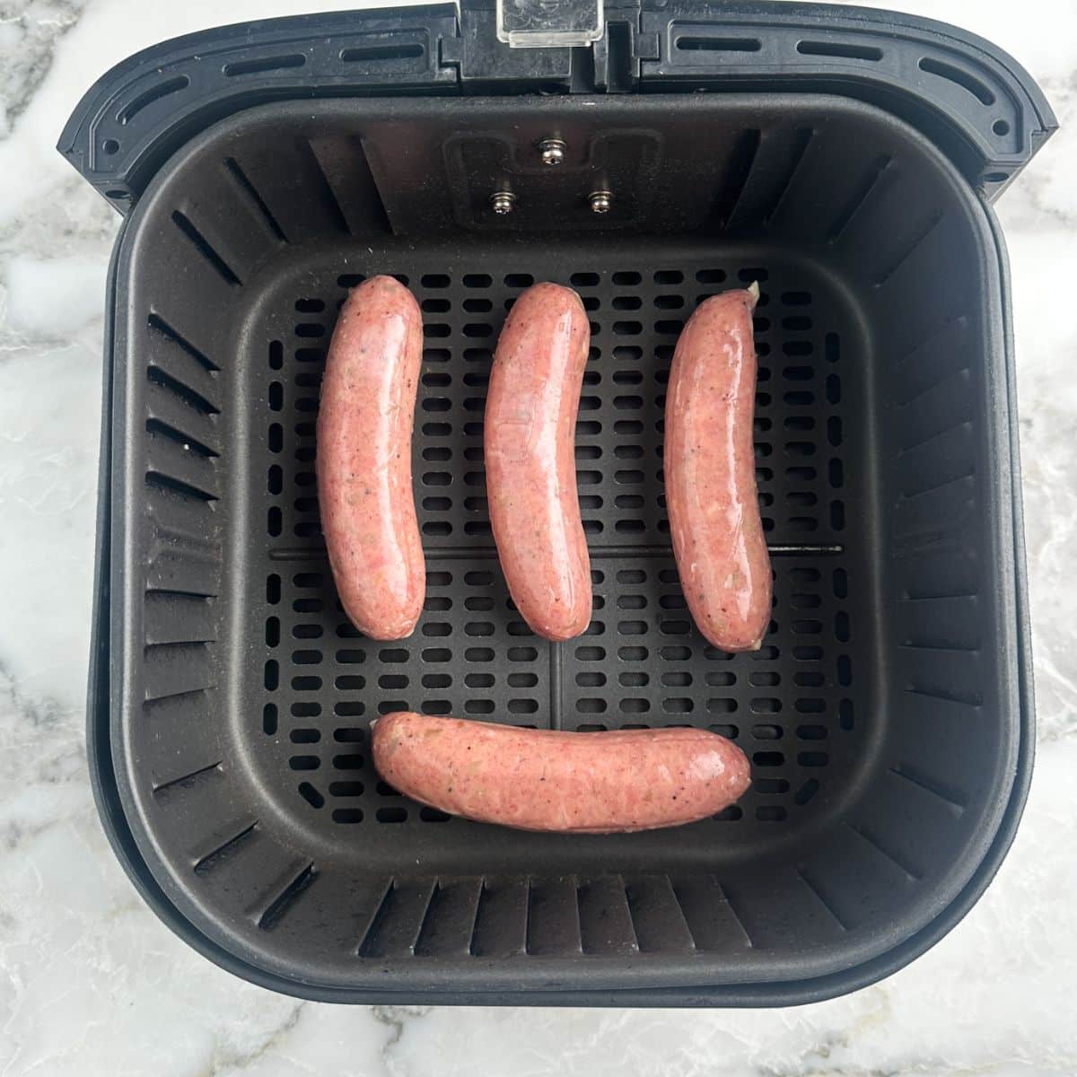 Air fryer basket with chicken sausage.