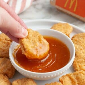 Bowl of sweet and sour sauce with chicken nugget.