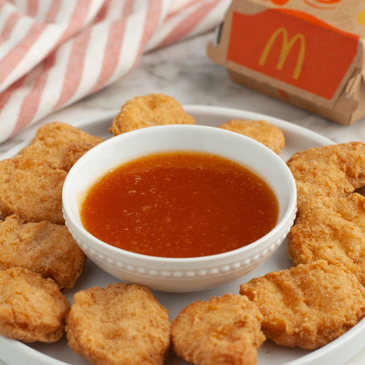 Plate with chicken nuggets and a bowl of sweet and sour sauce.