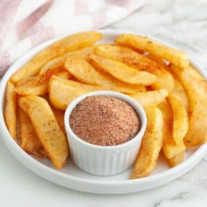 Plate of steak fries with a bowl of seasoning.