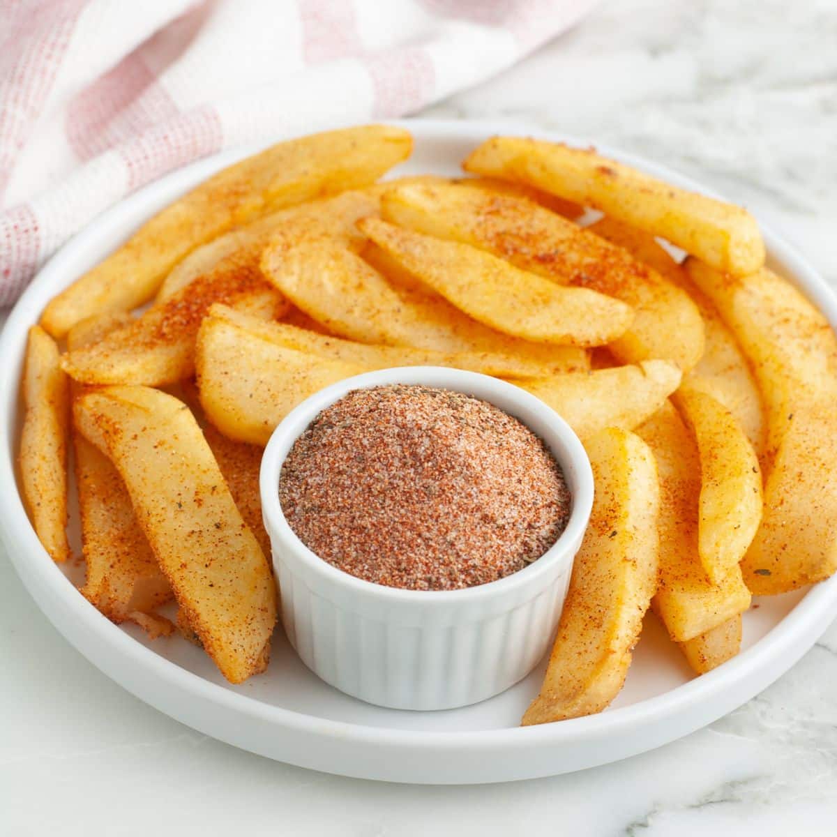 Plate of steak fries with a bowl of seasoning.